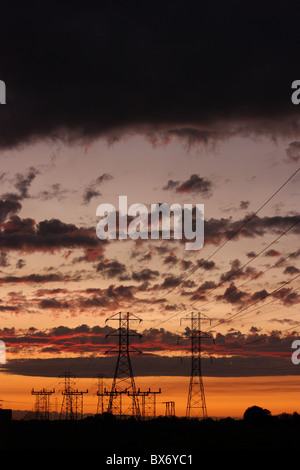 Sendemasten und Stromleitungen vor einem dramatischen Sonnenuntergang Himmel abhebt. Stanislaus County, Kalifornien Stockfoto