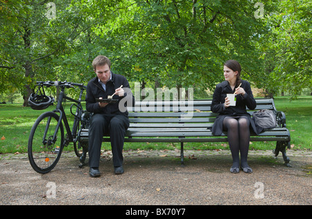 Frau und Mann isst Mittagessen auf Parkbank Stockfoto