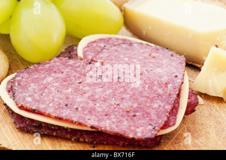 Herz Rennskier Salami mit Bergkäse und Trauben als Closeup auf ein Schneidebrett Stockfoto