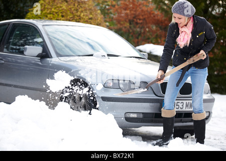 Frau aus dem Auto aus dem Schnee Graben Stockfoto