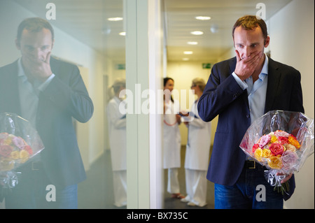 Überrascht Man mit Blumen im Krankenhaus Stockfoto