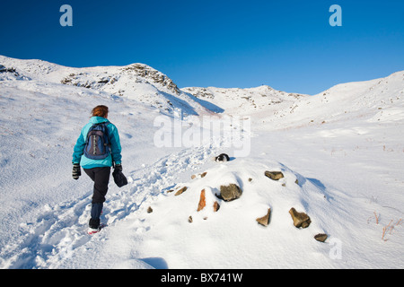 Eine Frau zu Fuß auf Loughrigg im Lake District, Großbritannien, im Winterwetter. Stockfoto