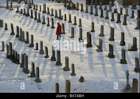 Eine Dame im roten Mantel unter Grabsteine auf dem Friedhof Stockfoto