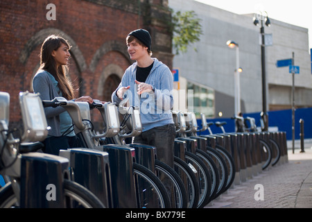 Junges Paar im Gespräch mit gemieteten Fahrrad Stockfoto