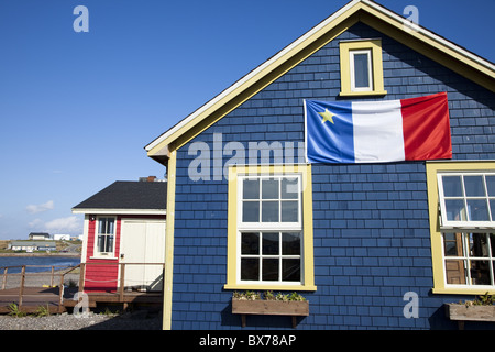 Acadian Flagge am blauen Haus in La Grave, Ile Havre-Aubert, eines der Iles De La Madeleine, St.-Lorenz-Golf, Quebec, Kanada Stockfoto