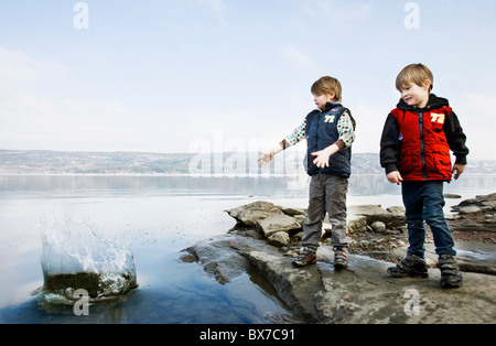 Jungs spielen mit Steinen am See Stockfoto