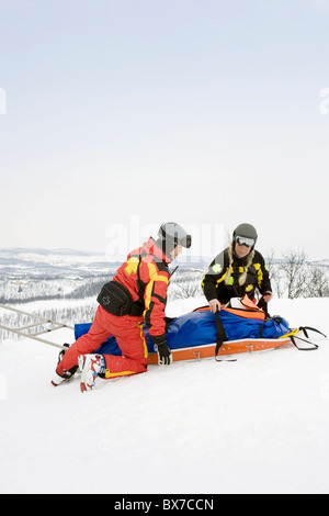 Zwei Retter helfen Skifahrer Stockfoto