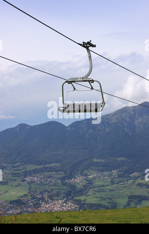 Leere Träger auf eine high-Speed Sessellift gegen ein bewölkter Himmel. Italienischen Alpen im Hintergrund. Stockfoto