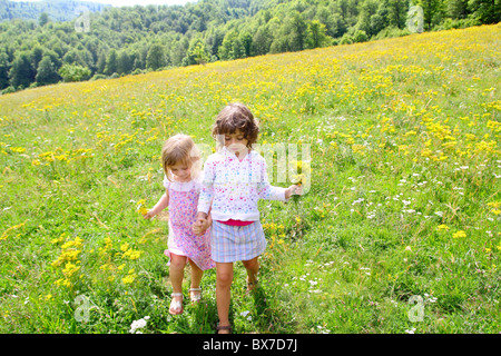 Schwester Mädchen auf Wiese spielen mit Frühlingsblumen im freien Stockfoto