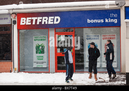 drei Jugendliche außerhalb Wetten Shop im Schnee Stockfoto