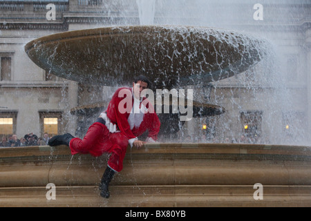 Als Weihnachtsmann verkleidet Santacon 2010, Flashmob Zusammenkunft von Menschen im Zentrum von London. Santa in Trafalgar Square Brunnen. Stockfoto