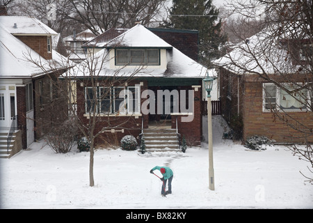 Frau Schaufeln Schnee vom Gehsteig. Stockfoto