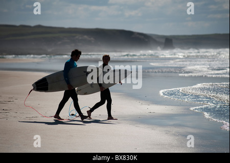 Zwei junge Surfer einem Strandspaziergang in Richtung Meer an einem herrlichen Sommertag in Cornwall England Stockfoto