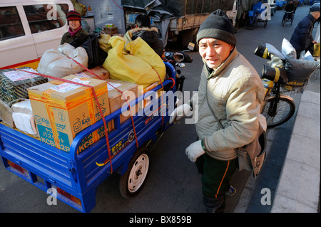 Kuriere des lokalen Shentong Express erhalten Pakete auf einem motor Dreirad in einem Umspannwerk in Peking, China geliefert werden. 2010 Stockfoto