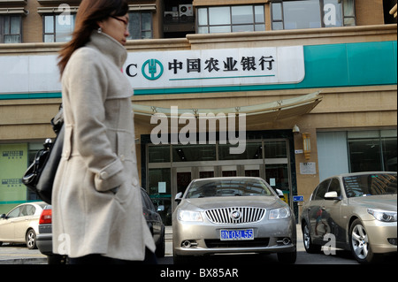 Eine Frau geht vorbei an einem Zweig der Agricultural Bank of China in Peking, China.12-Dec-2010 Stockfoto