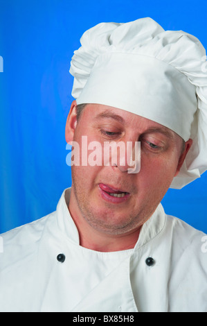 Der weiße Mann auf blauem Hintergrund in der Kleidung des Kochs Stockfoto