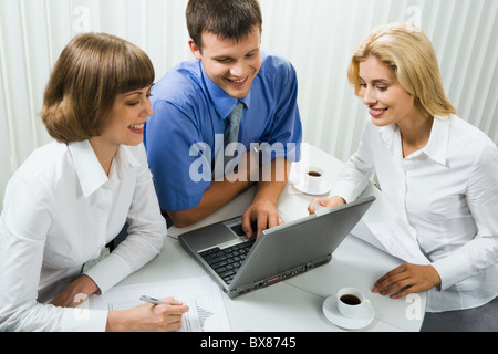 Gruppe von jungen Spezialisten versammelt um den Laptop über wichtiges Projekt im Büro Stockfoto