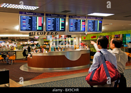 Zwei asiatische Männer anzeigen Flugzeug Zeit Abfahrt und Ankunft Zeitpläne auf CRT monitor bei Flughafen Stockfoto