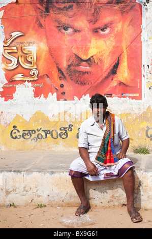 South Indian Mann vor eine schäbige alte Filmplakat sitzend. Andhra Pradesh, Indien Stockfoto