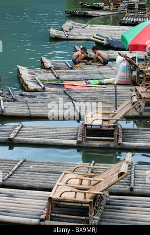 Zwei Jungen spielen zusammen auf Bambus Flößen vertäut entlang der Yulong Fluss, Yangshuo, Guangxi, China. Stockfoto