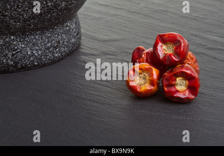 Getrocknet, lebendige Chili auf dunklem Schiefer mit Mörser und Stößel. Stockfoto