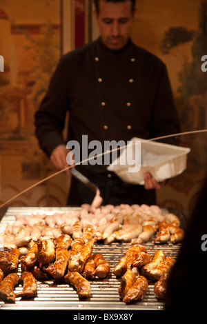 Mann Kochen Bratwurst Wurst für Käufer auf einen Stand auf dem Rathausplatz-Weihnachtsmarkt in Hamburg. Stockfoto