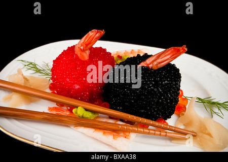 Nigiri Sushi bedeckt in roten und schwarzen Fisch Eiern mit Wasabi und Ingwer. Mit zwei Stäbchen. Auf schwarz. Stockfoto