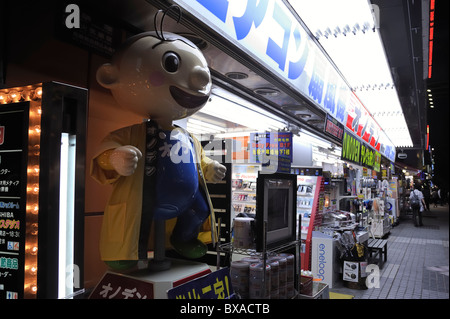 Typische Elektrogeschäft mit starker Beleuchtung und comic-Figur in Akihabara in der Nacht, Tokyo, Japan Stockfoto