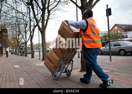 Ein Kurier verwendet einen Trolley, um schwere Pakete zu bewegen. Stockfoto