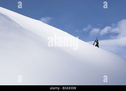 Ein Skifahrer Wandern auf einem verschneiten Bergrücken mit Ski auf der einen Seite in Andermatt in der Schweiz. Stockfoto