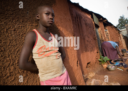 Ein Junge steht alleine vor einem Lehmhaus in Jinja, Uganda, Ostafrika. Stockfoto