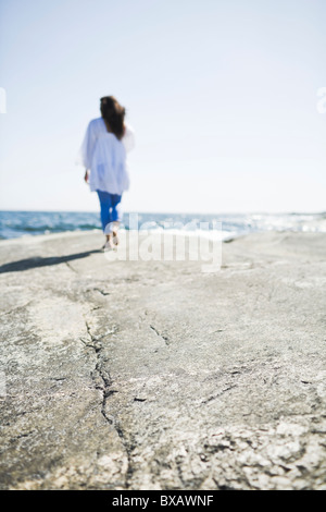 Frau zu Fuß auf Felsen auf dem Seeweg Stockfoto