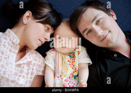 Babymädchen liegen zwischen Vater und Mutter Stockfoto