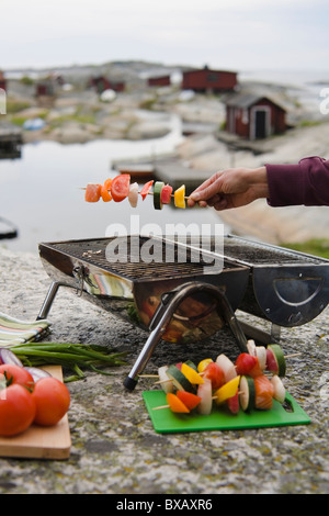 Menschliche Hand halten-Spieß mit Gemüse über grill Stockfoto