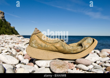 Alte beschädigte Schuh am Steinstrand Stockfoto