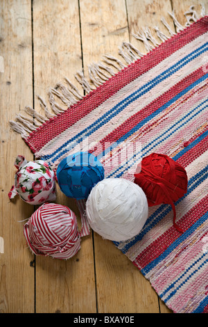 Kugeln aus Wolle und gestrickter Teppich auf Holzboden Stockfoto