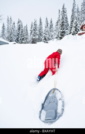 Kind ziehen Schlitten bergauf in Winterlandschaft Stockfoto