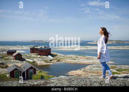 Frau auf Felsen mit Häusern im Hintergrund Stockfoto