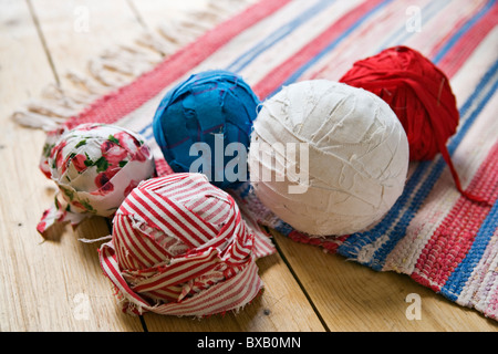 Nahaufnahme - Kugeln aus Wolle und gestrickter Teppich auf Holzboden Stockfoto