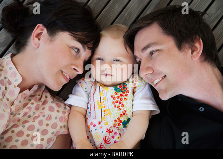 Babymädchen liegen zwischen Vater und Mutter Stockfoto