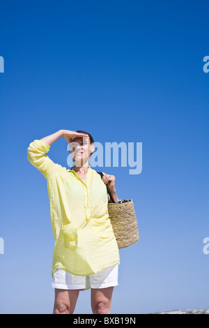 Frau mit Strandtasche und Abschirmung Augen Stockfoto