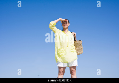 Frau mit Strandtasche und Abschirmung Augen Stockfoto