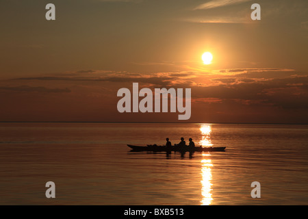 Menschen im Ruderboot bei Sonnenuntergang Stockfoto