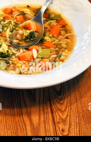 Gute herzhafte hausgemachte Gemüsesuppe in strukturierte weiße Schüssel auf Holz Küchentisch serviert. Stockfoto