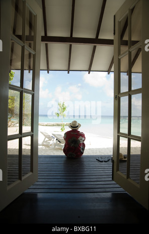 Mann sitzt auf der Holzterrasse auf den Malediven Stockfoto