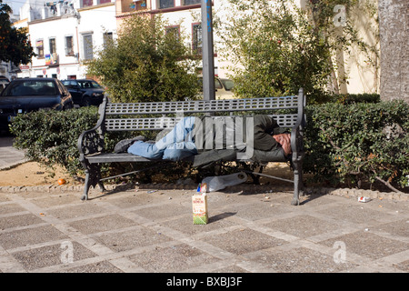 Ein Obdachloser schläft auf einer Bank in einer Straße, Sevilla, Spanien Stockfoto