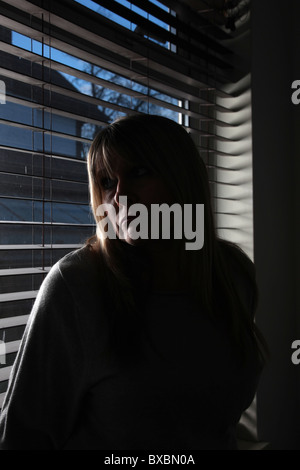 Porträt einer fair dunkelhaarige Frau aus einem Fenster, depressiv Stockfoto