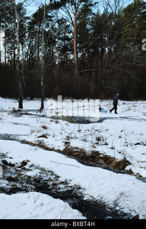 Vater Sohn auf Schlitten durch tief verschneite Landschaft ziehen Stockfoto