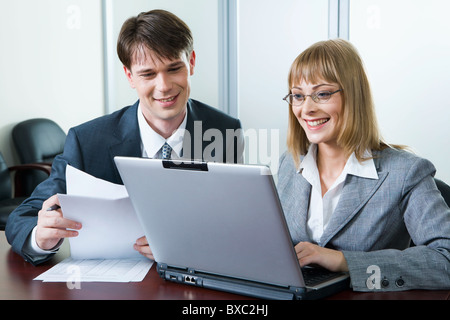 Konzentriert, Geschäftsmann und lächelnde junge Frau am Tisch auf dem laptop Stockfoto