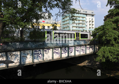 S-Bahn auf Seite Schiene Kanalbrücke geschmückt mit Graffiti im Regents Park Road in Primrose Hill. Stockfoto